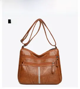 Detailed view of brown textured leather crossbody bag with multiple zippers and rhinestone trim