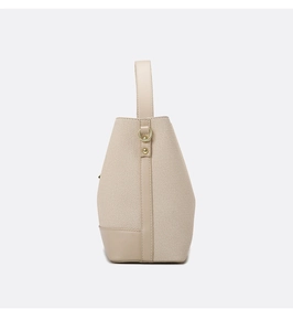 Detailed side view of beige canvas and leather bucket bag with metallic D-ring buckle