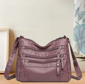Detail view of purple soft leather crossbody bag with multi-zipper pockets and metal rivets