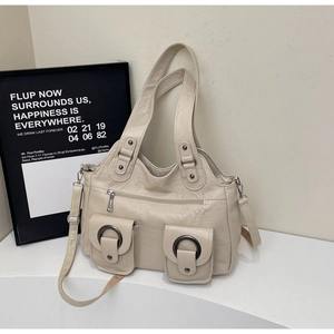 Detail of beige tote bag featuring two front pockets with round metal hardware buckles
