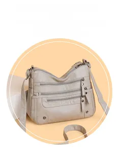 Detail view of multi-pocket soft faux leather crossbody bag with zipper compartments