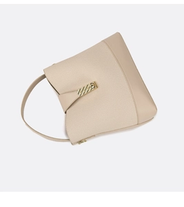 Detail of beige bucket bag featuring a textured canvas body and golden metal buckle