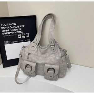 Detail view of grey faux leather tote bag with dual front pockets and metallic hardware