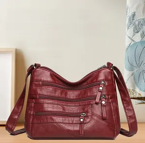 Detail view of burgundy soft leather bag featuring multiple front zipper compartments