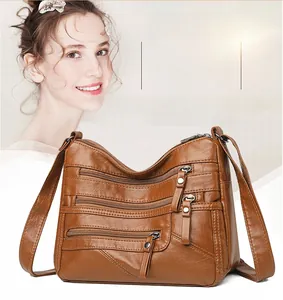 Detail view of brown soft leather shoulder bag with multiple zip pockets and hardware