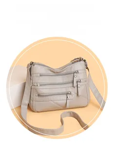 Detail view of cream soft leather shoulder bag featuring four front zipper pockets