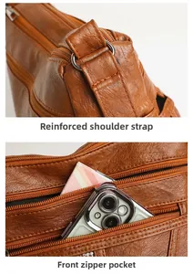 Detail of reinforced shoulder strap and front zipper pocket on brown leather tote