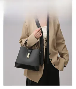 Detail of grey fabric bucket bag with gold chain lock on beige blazer model