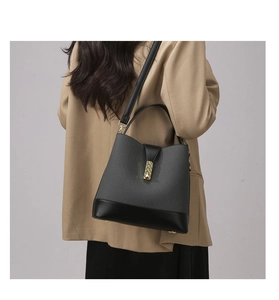 Detailed view of bicolor fabric bucket bag with gold clasp shown on a model