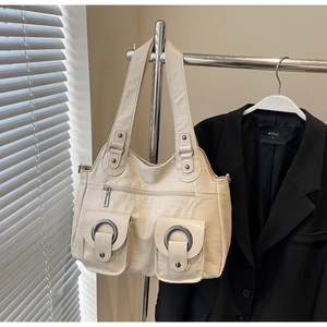 Detail of off-white faux leather tote bag with functional pockets and metal ring buckles