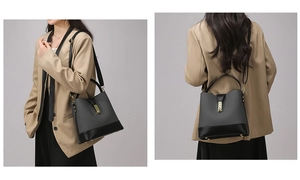 Detail of dark grey leather bucket bag featuring black stitching and gold metal lock