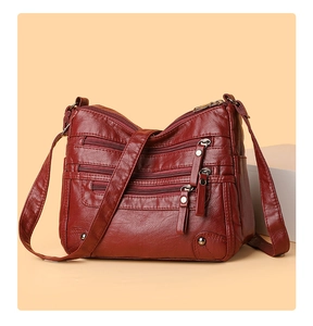 Detail view of wine red multi-zippered crossbody bag with soft textured leather finish