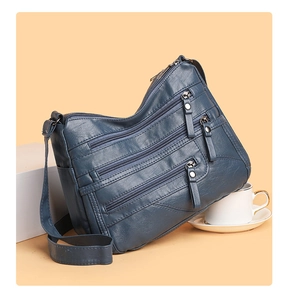Detail view of large navy blue crossbody bag with multiple silver zipper pockets