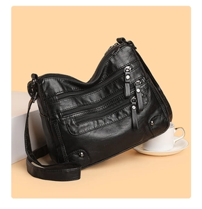 Detail of soft black PU leather shoulder bag featuring multiple functional zippers and studs