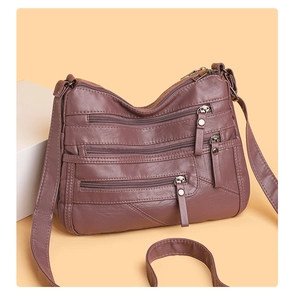 Detail view of mauve soft leather crossbody bag with multiple functional zip pockets