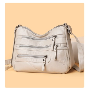 Detail view of large capacity soft leather crossbody bag with multiple zipper pockets