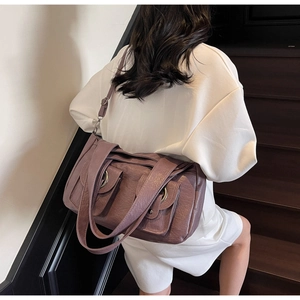 Detail of purple tote bag showing dual front flap pockets and retro metal rings