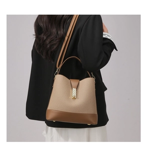 Detail of vintage beige fabric bucket bag with brown leather trim and gold metal lock