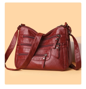 Detail view of burgundy faux leather crossbody bag with multiple zipper pockets