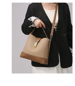 Detail of canvas bucket bag showing gold chain buckle and brown leather trim