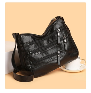 Detail shot of black multi-zipper compartments on a soft faux leather shoulder bag