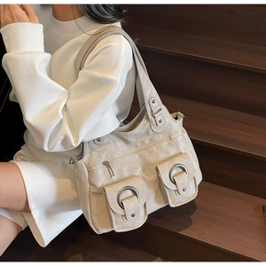 Close-up of cream vintage tote bag with dual metallic ring pockets on soft pleated faux leather