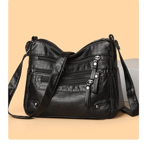 Detail view of multi-pocket soft black leather crossbody bag with silver zippers
