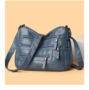 Close-up of deep blue textured leather bag showing multiple functional zipper pockets