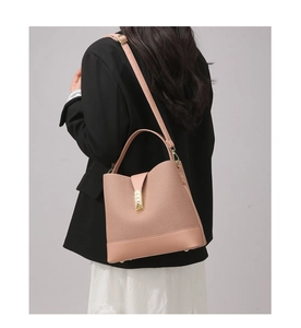 Detailed view of a pink bucket bag featuring a woven texture and smooth leather finish