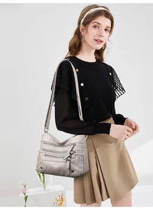 Detail of light grey multi-pocket crossbody bag with soft leather texture and zippers