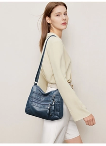 Detail of soft leather crossbody bag with multiple pockets and silver zippers on model
