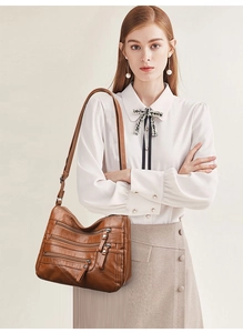 Brown multi-pocket crossbody bag worn by a model in a casual retro styling detail