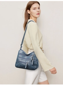 Detail view of navy blue soft leather shoulder bag with multiple zippered compartments