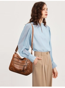 Detail of soft dark brown crossbody bag with multi-zipper pockets and wide shoulder strap