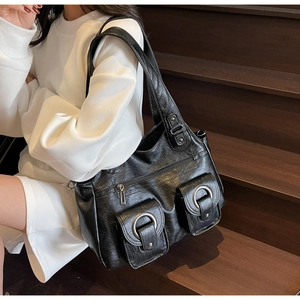 Detailed view of black retro shoulder bag with metallic rings and dual front pockets