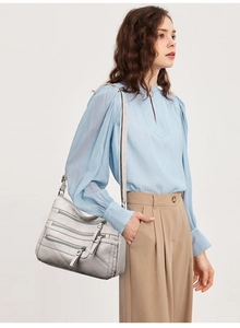 Light grey multi-zipper shoulder bag shown on model for size and capacity reference
