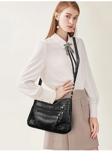 Detail of soft black leather shoulder bag showing multiple zipper pockets and silver rivets