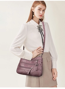 Detail view of deep purple soft faux leather crossbody bag with multi-pocket zippers