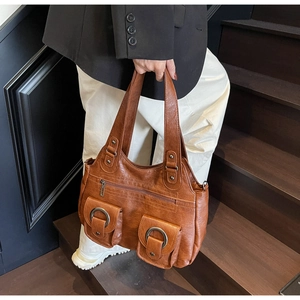 Detail view of a vintage dark brown leather tote with front flap pockets and metal rings