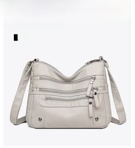 Detailed view of light grey soft leather shoulder bag with multiple zipper pockets