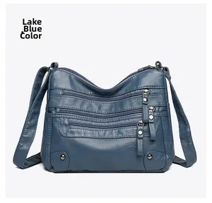 Close-up of lake blue soft leather bag featuring multiple functional zipper pockets