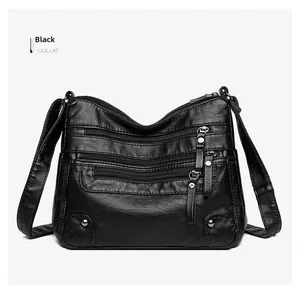 Detail view of black textured leather crossbody bag featuring multiple front zip pockets