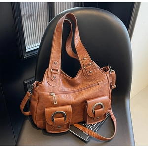 Detail of vintage brown leather tote bag featuring dual front pockets with large metal rings