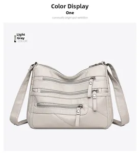 Detailed view of light grey textured leather bag with multiple front zipper pockets