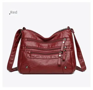 Detail of red faux leather shoulder bag with multi-pocket zippers and pebbled texture