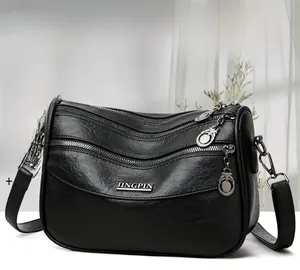 Detailed view of black multi-layer shoulder bag with silver zippers and textured faux leather