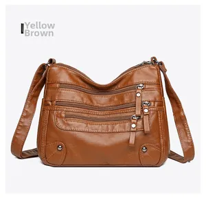 Detailed view of the yellow-brown soft leather shoulder bag with multiple zippered pockets