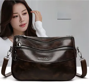 Detail of dark brown leather crossbody bag with multiple zippers and metallic logo