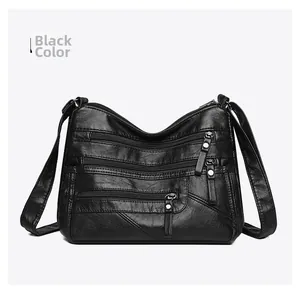 Detail of black faux leather crossbody bag showing multiple zip pockets and texture