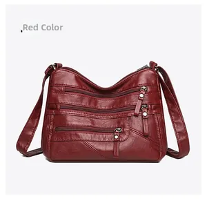 Detail of red soft leather crossbody bag showing three zippered compartments and texture